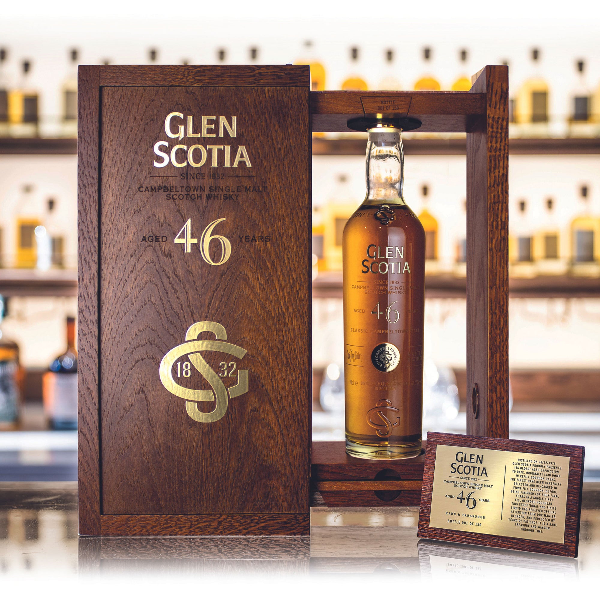 A bottle of Glen Scotia 46 Year Old Whisky is displayed with its wooden box open behind it. The bottle, adorned with a gold cap and a detailed label, boasts rich flavors from its first fill bourbon cask, while the box features gold accents detailing the whisky's age and origin.