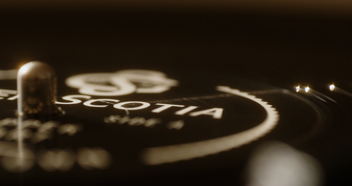 Close-up of a vinyl record. The photo focuses on a section near the center, showcasing part of the label with slightly blurred text and graphics. The words &quot;The Sound of Glen Scotia&quot; stand out, reminiscent of the rich heritage found in Campbeltown&#39;s Glen Scotia distillery. The grooves of the vinyl are slightly visible.
