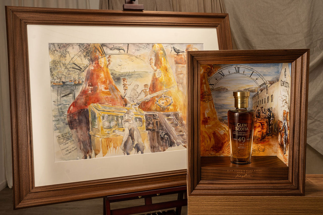 Framed painting with a distillery scene showing copper stills and workers on the left. In front of it, there is a smaller wooden frame containing a Glen Scotia 49-year-old single malt Scotch whisky bottle, displayed in front of another distillery illustration.
